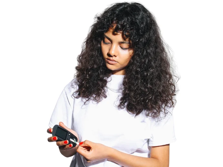 A young woman is testing blood sugar levels using a glucosimeter